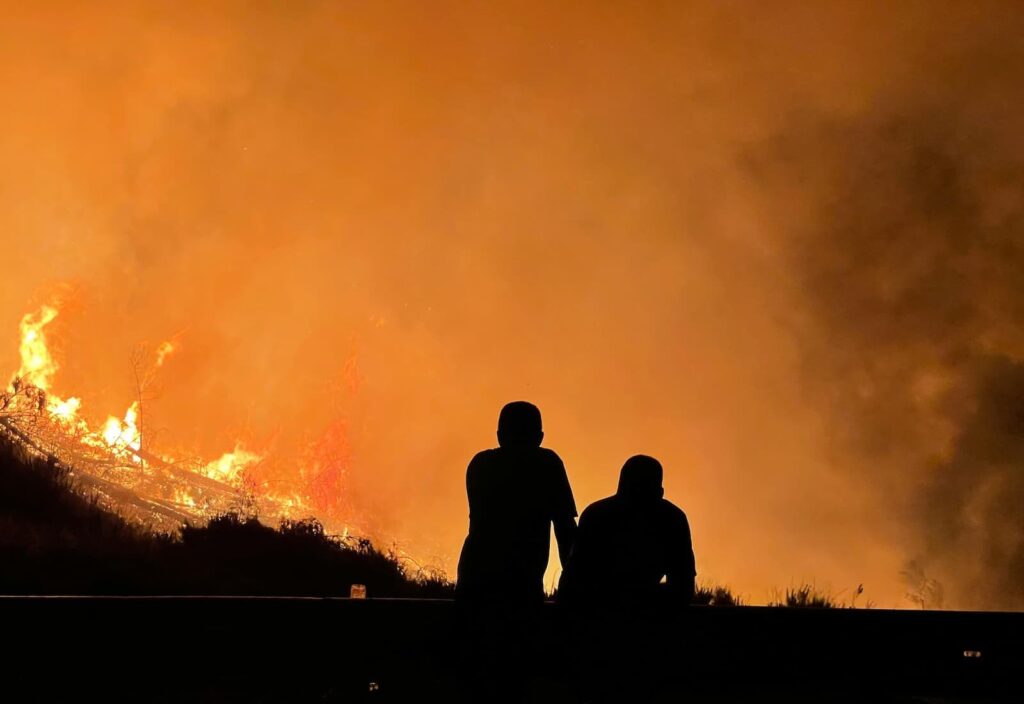 Silhouettes of two people watching a wildfire