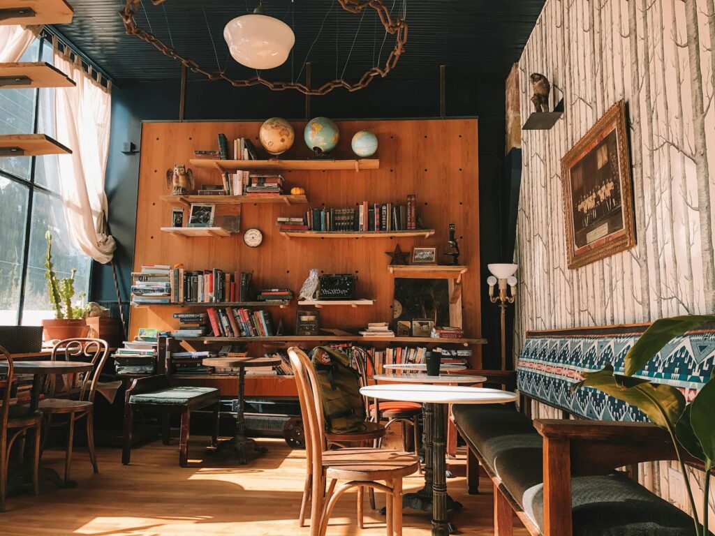 A cozy cafe with many books and pieces of wooden furniture