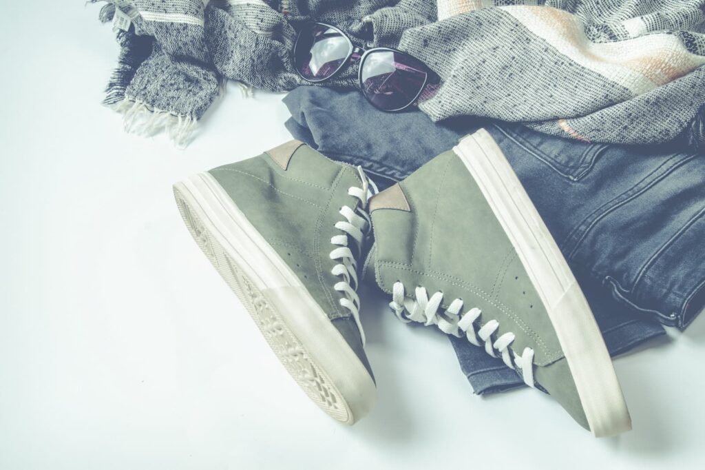 A pair of sneakers, jeans and sunglasses lying on the floor