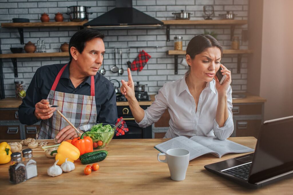 A woman gesturing for a man to wait until she is finished talking on the phone