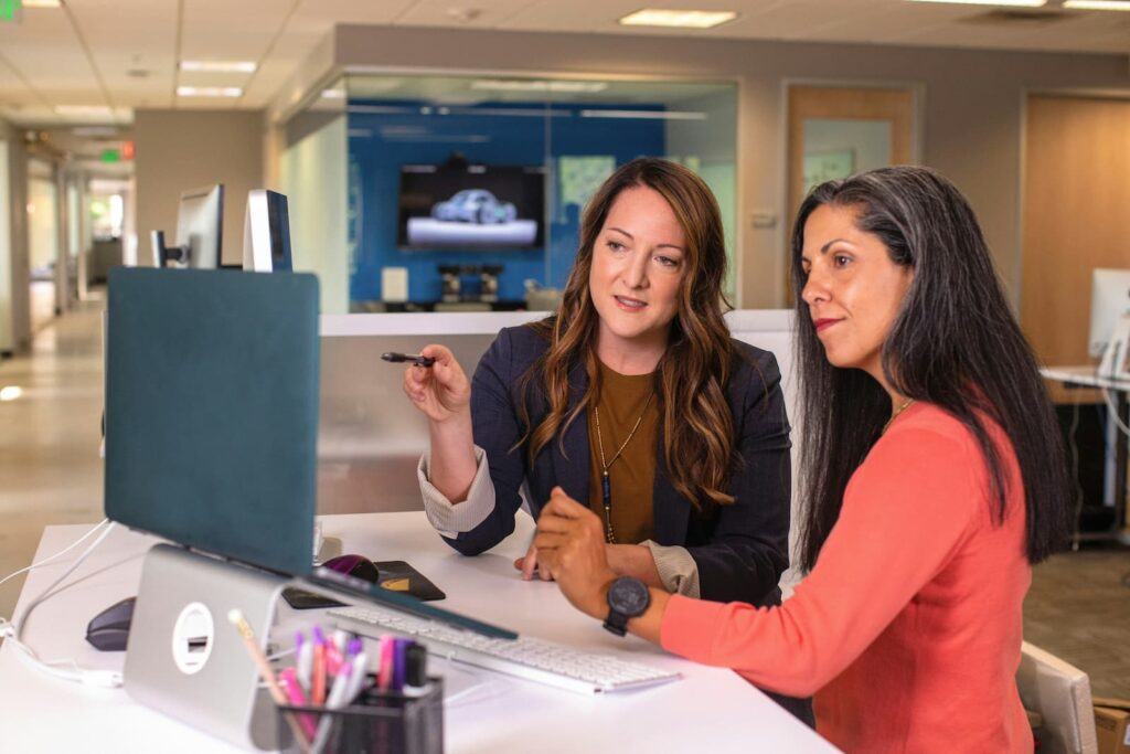 Two women working on a computer in an office environment