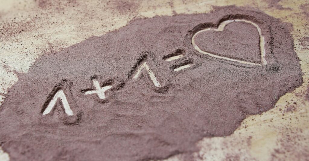 "1 + 1 = heart" written in sand