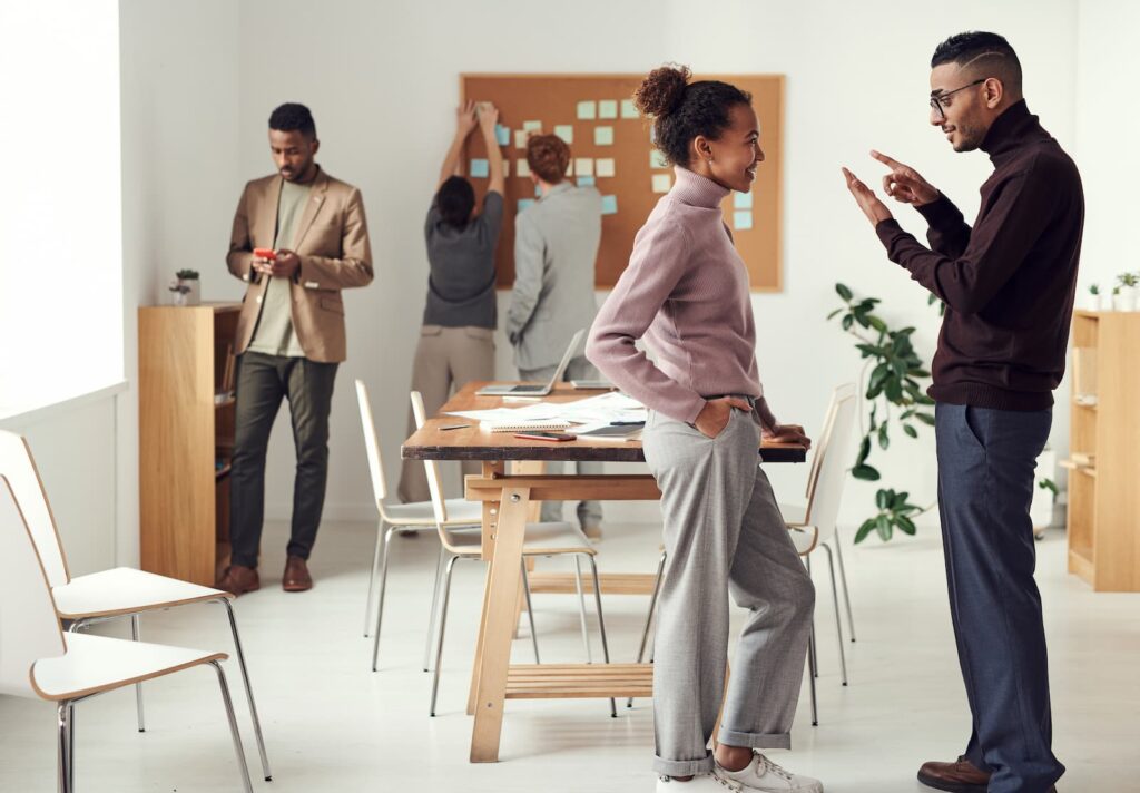 Two young professionals speaking to one another in a casual office environment
