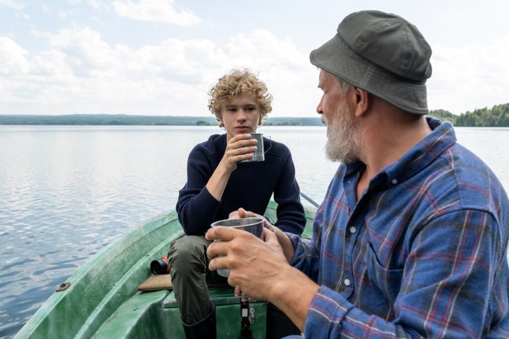A man having a conversation with his grandson on a small fishing boat