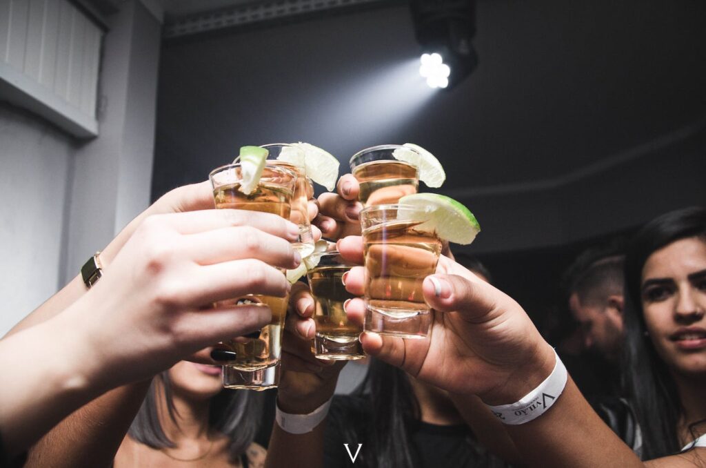 A group of people toasting at a party by raising their drinks in the air
