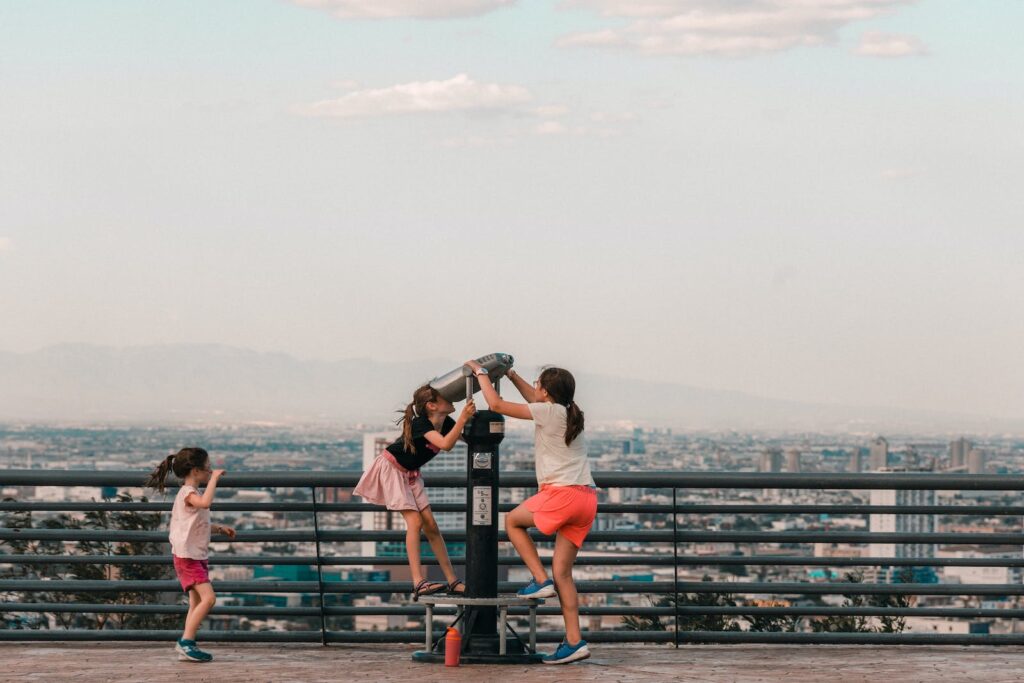 Children looking into the sky using a device in a public area