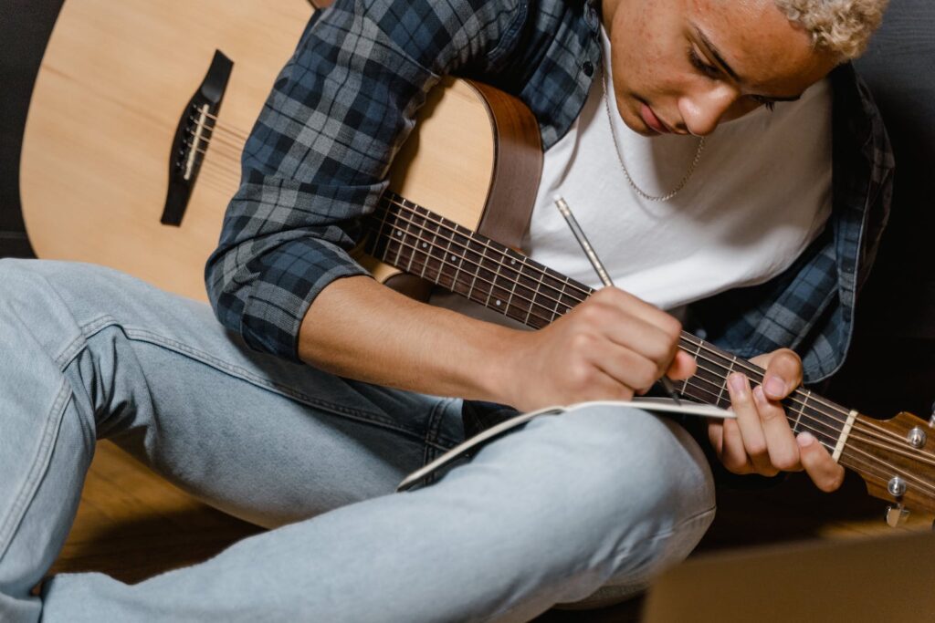 A musician writing a song while holding his guitar