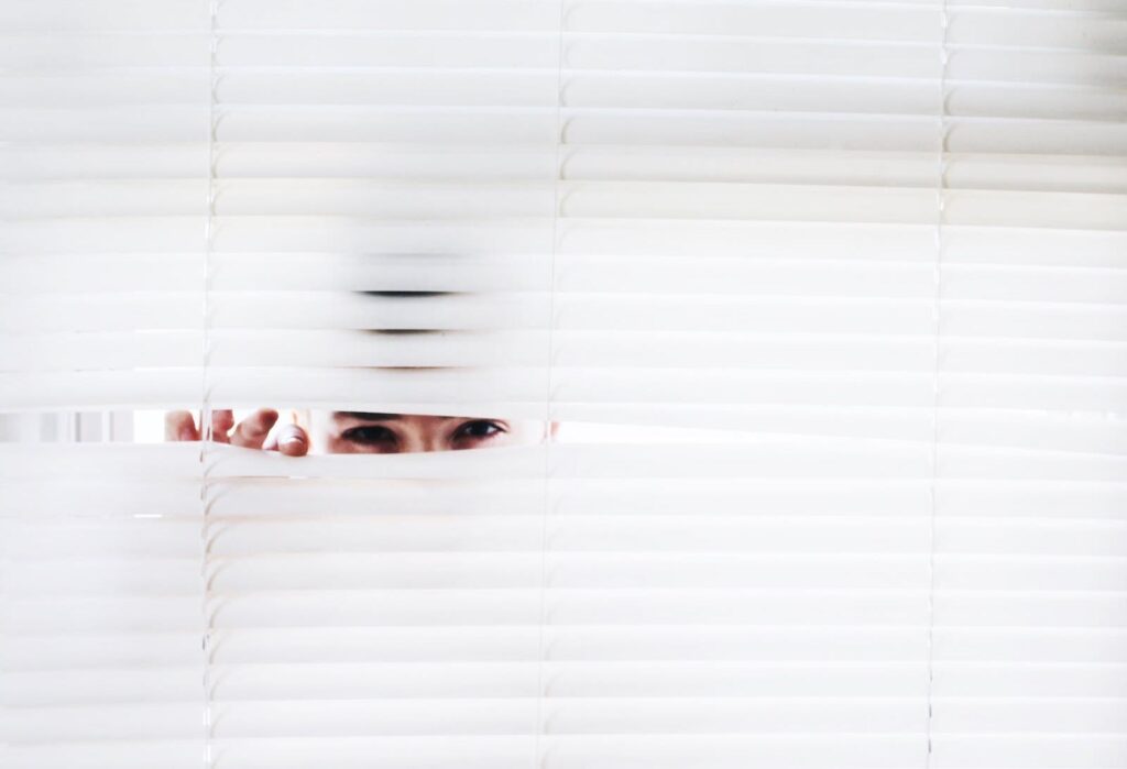 A man peeking through window blinds