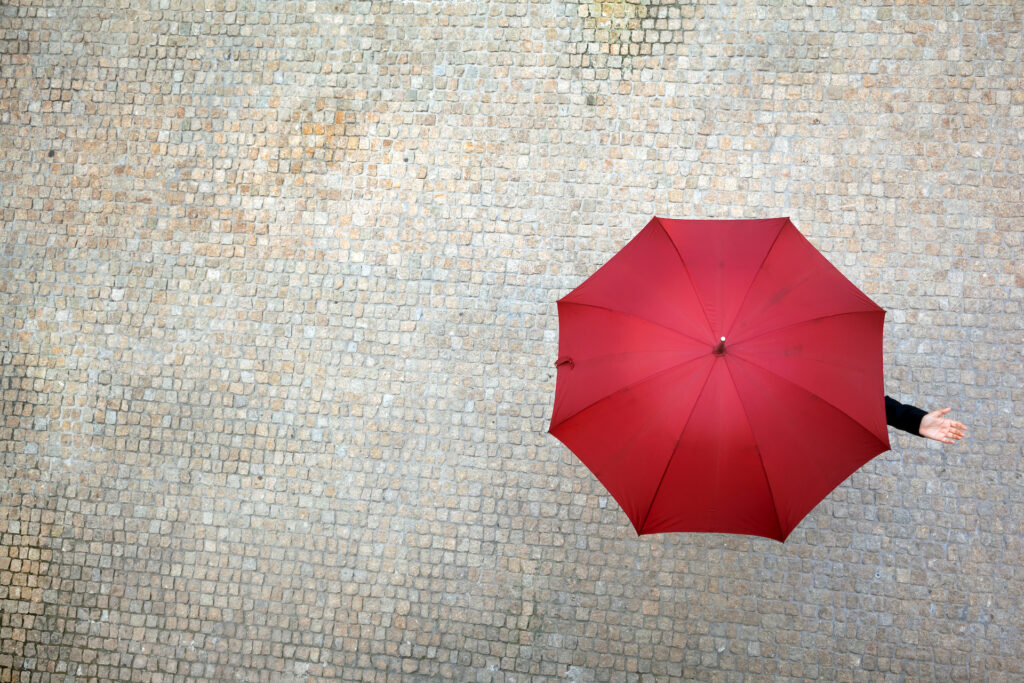 A woman under an umbrella checking to see if it's raining