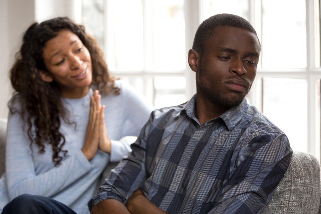 A young woman trying to apologize to her boyfriend who is still upset with her