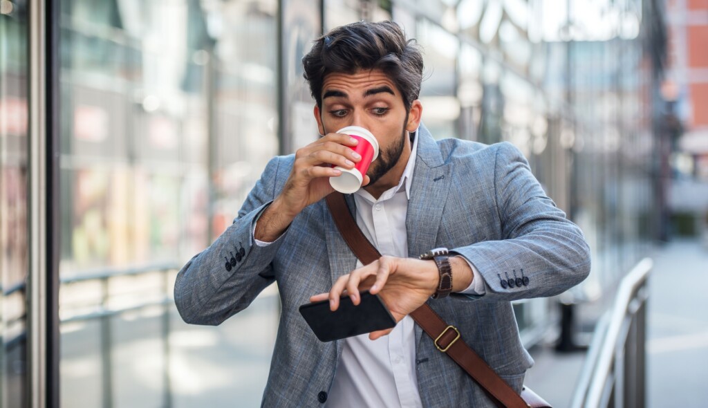 A businessman who is slightly late looking at his watch on the way to a meeting