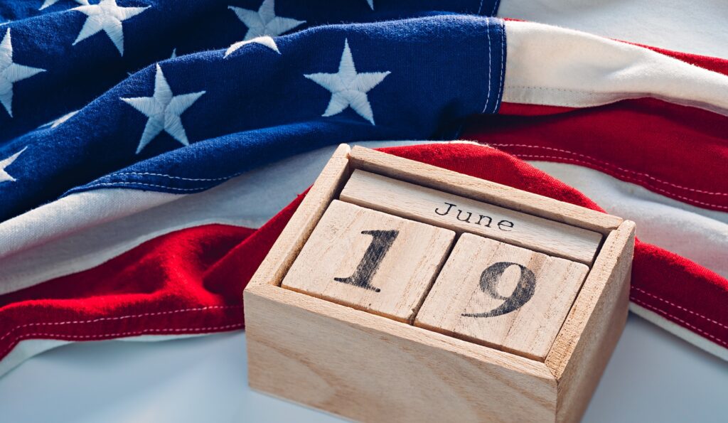 An American flag lying against a calendar set to June 19, or Juneteenth National Independence Day