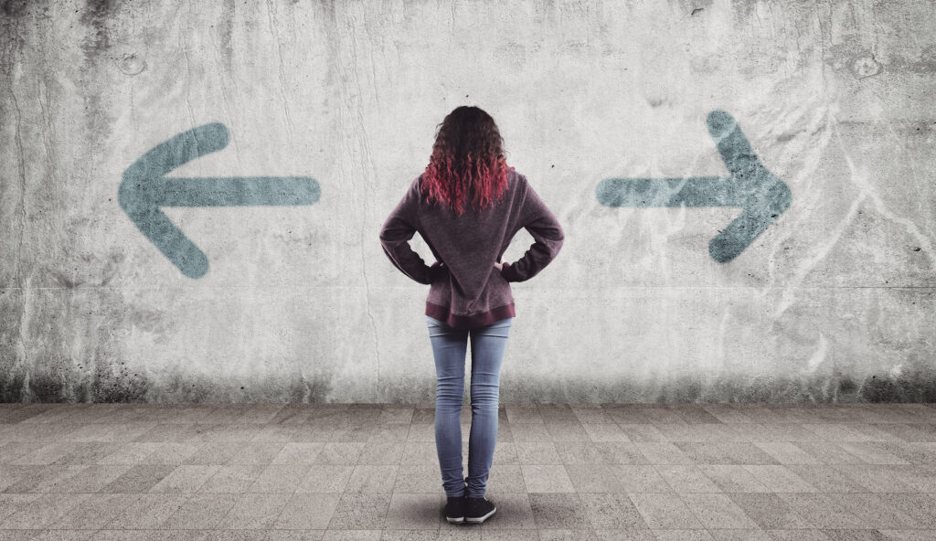 A woman standing in front of a wall that has been painted with an arrow pointing left and another pointing right