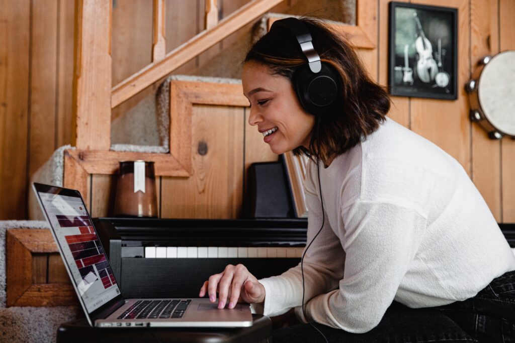 A young woman wearing headphones while sitting in front of her computer