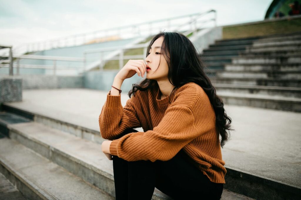 A seated woman thinking while touching her lips with one hand