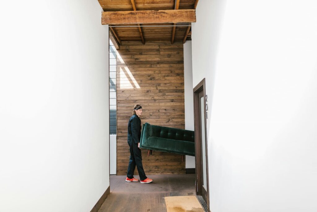 A man carrying one side of a sofa into an apartment