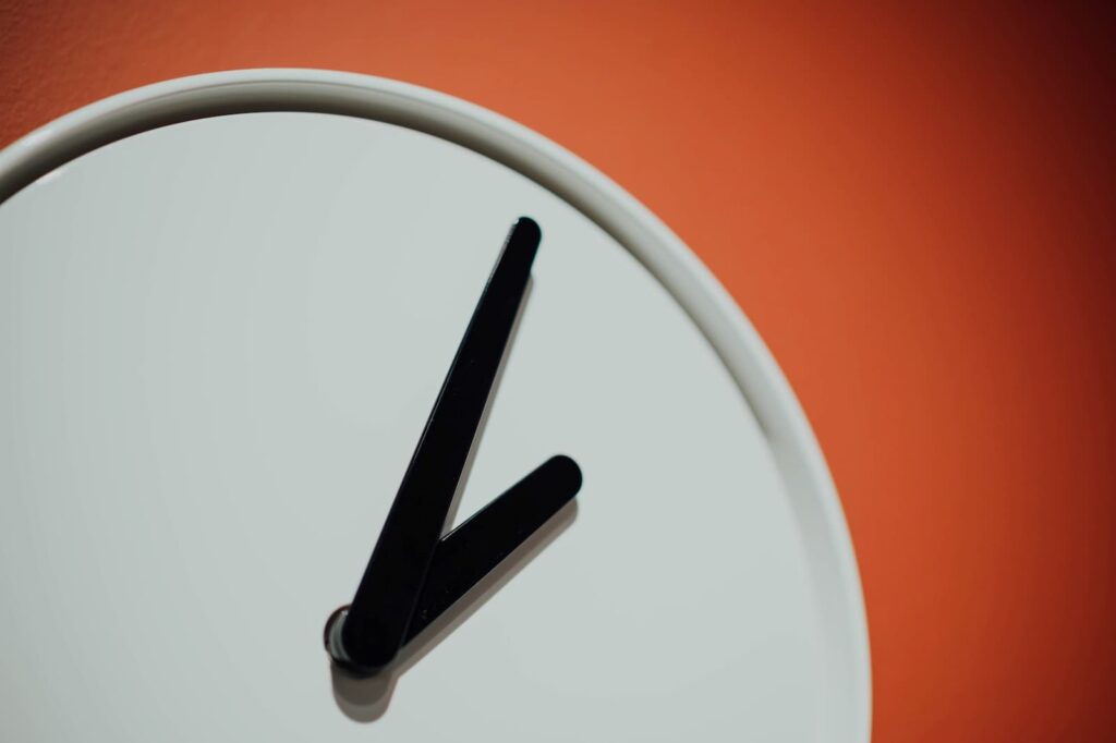 A close-up of a white clock against an orange background