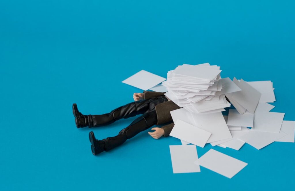 A businessman toy figure covered by small documents