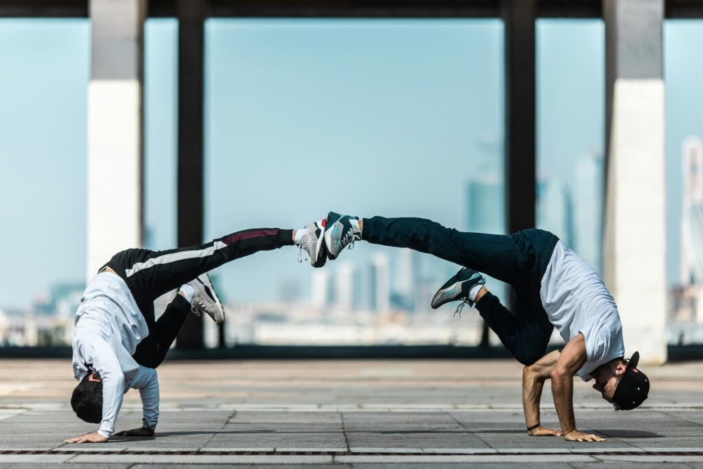 Two b-boys performing a freeze in an outdoor city area